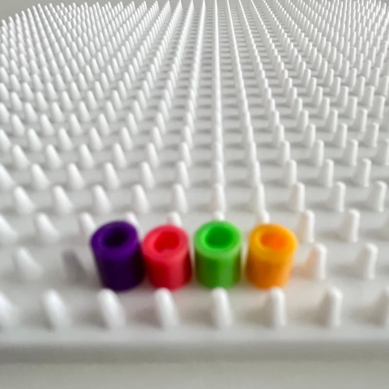 Child creating patterns with colorful Hama beads on a pegboard
